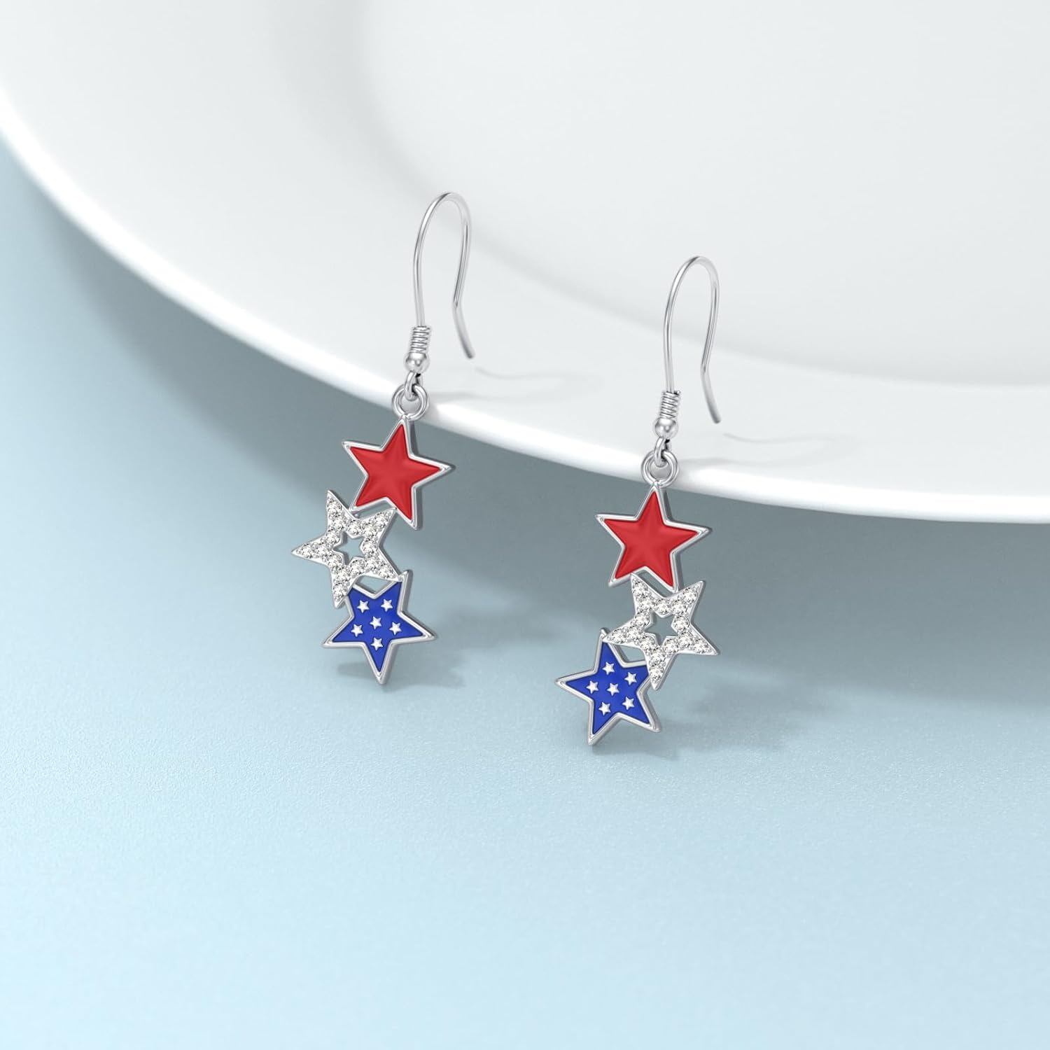 Patriotic star dangle earrings in sterling silver resting on light blue surface