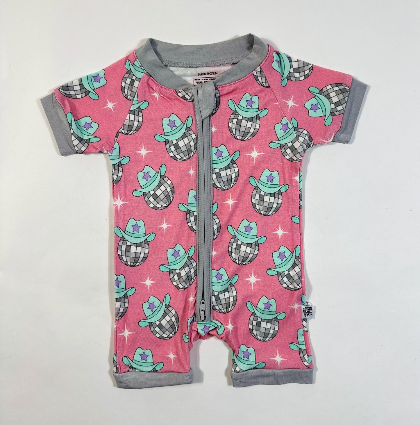 Pink baby romper with cowboy hat pattern on a white background