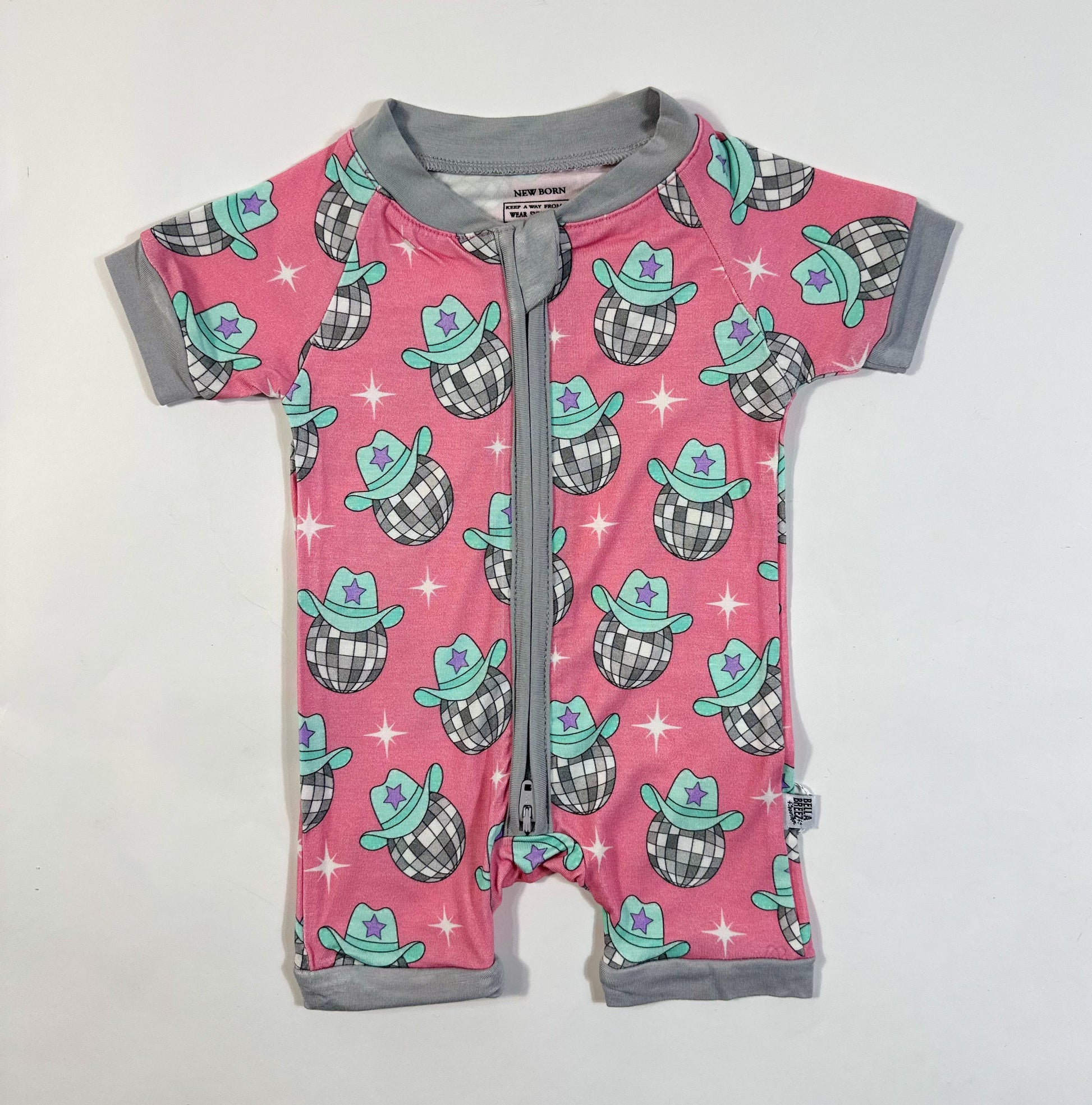 Pink baby romper with cowboy hat pattern on a white background