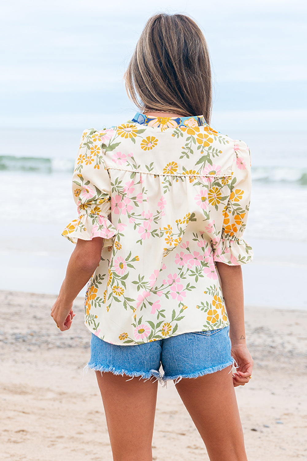 Peasant style floral blouse back view showcasing puffed sleeves and ruffled cuffs