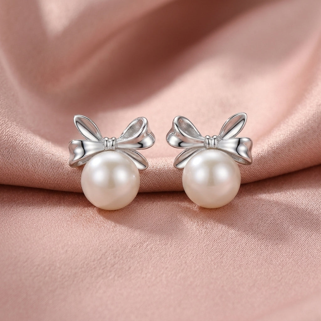 Sterling Silver Elegant Bow Knot Pearl Stud Earrings on Blush Pink Silk Backdrop